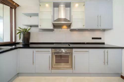 a kitchen with white cabinets and a stove top oven at 4BR Penthouse Royal Marina 6B Private Rooftop Pool with 360 View in Phuket