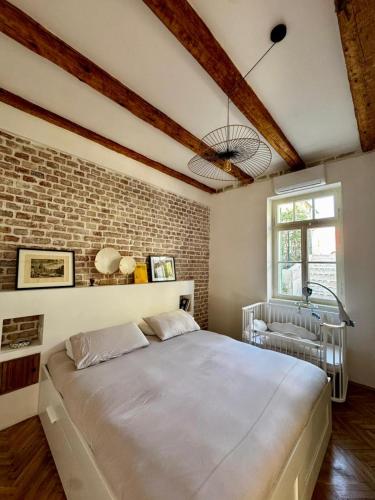a large bed in a room with a brick wall at Exceptional Home-5 min from Porto Montenegro Tivat in Tivat