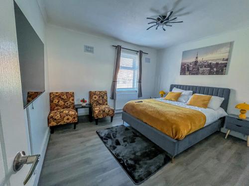 a bedroom with a bed and two chairs and a window at Eugino Properties in Grays Thurrock