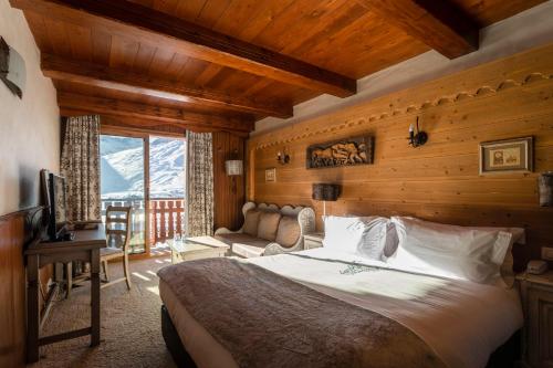 a bedroom with a bed and a couch and a television at Hôtel les Campanules by Les Etincelles in Tignes