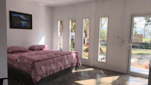 a bedroom with a bed and two large windows at บ้านสวนร่มไม้แอ๊ดเชียงดาว in Ban Hua Thung