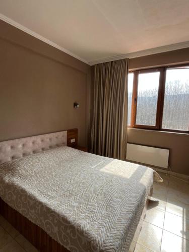 a bedroom with a bed and a large window at Kompleks Koral Konak in Prezhda