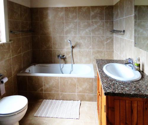 a bathroom with a tub and a sink and a toilet at Kleingeluk Guest Farm in De Rust