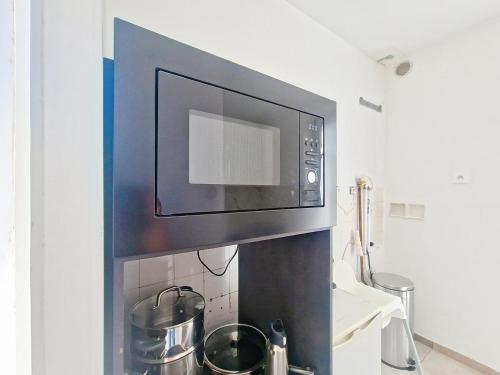 a microwave above a kitchen counter with pots and pans at Bel Appart 10 min de Paris et Orly in Juvisy-sur-Orge