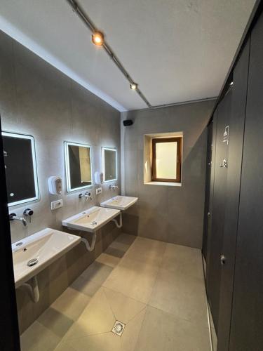 a bathroom with two sinks and two mirrors at Shkodra Hostel & Day Tours in Shkodër