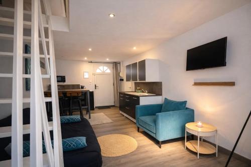 a living room with a blue couch and a kitchen at Le petit nid de St-Germain in Saint-Germain