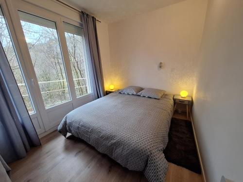 a bedroom with a bed and a large window at Escapade au Lac in Corancy