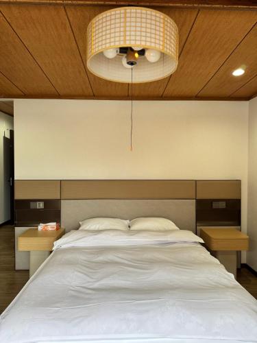 a bedroom with a large white bed and a light at Kurmon Inn in Omachi