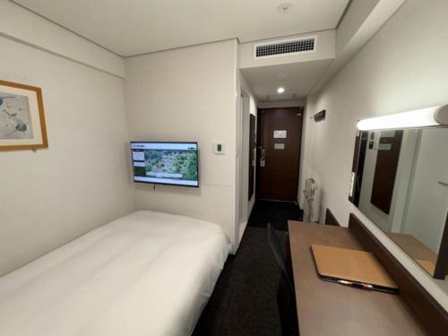 a hotel room with a bed and a television at Hotel Alpha-One Niihama in Niihama