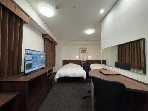 a hotel room with a bed and a desk with a computer at Hotel Alpha-One Niihama in Niihama