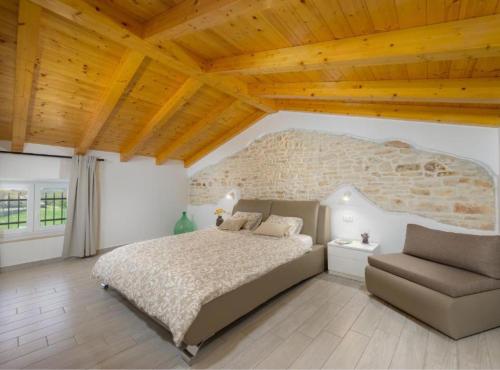 a bedroom with a bed and a couch and a stone wall at Villa Prestige Azinetti with Pool in Štokovci