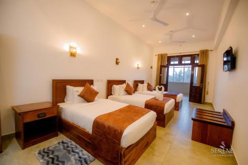 a hotel room with two beds and a television at Serene Lake View Resort in Anuradhapura