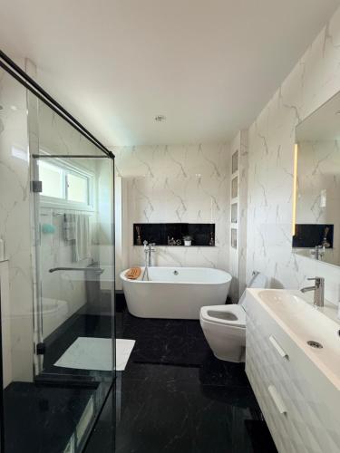 a bathroom with a tub and a toilet and a sink at Bluesky Villa Bang Sare in Bang Sare