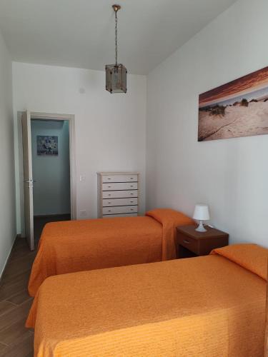 two beds in a bedroom with orange sheets at Appartamento Serenity in Marina di Ascea