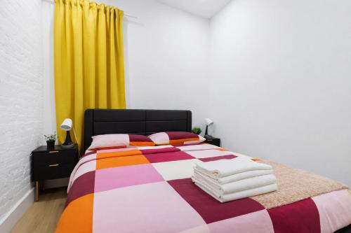 a bedroom with a colorful bed with a yellow curtain at 2 Bedroom Modern Unit in Central Manhattan in New York