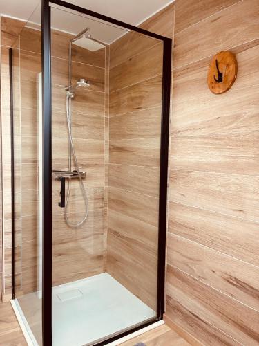 a shower in a bathroom with wooden walls at La Villa Delsa in Namur
