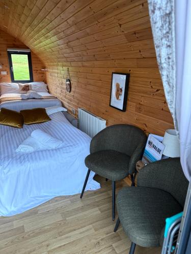 a bedroom with a bed and two chairs in a room at Squirrel's Drey in Torphichen