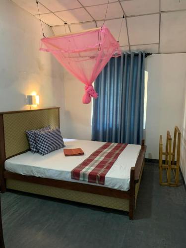 a bedroom with a bed with a pink umbrella on it at Pap De Home in Weligama