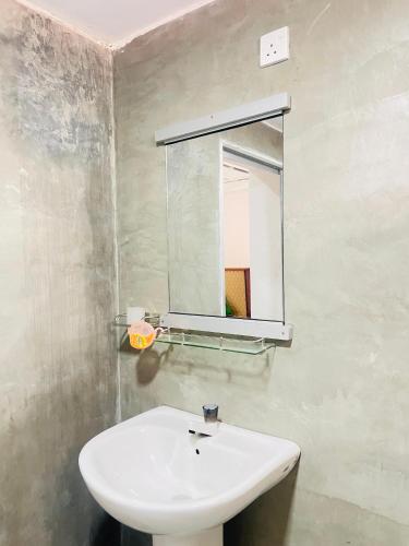 a bathroom with a white sink and a mirror at Pap De Home in Weligama