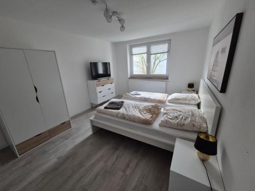 a white bedroom with two beds and a window at Schöne Ferienwohnung in Landsberg in Landsberg