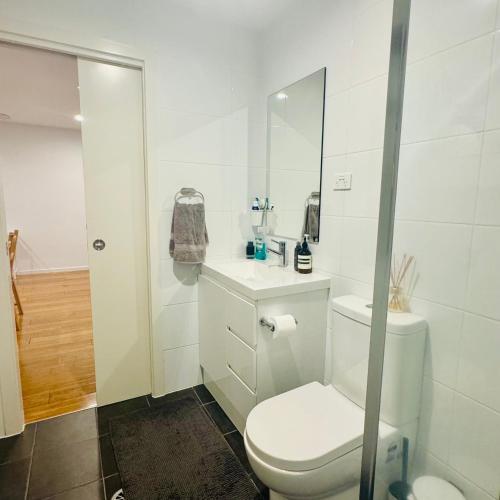 a white bathroom with a toilet and a sink at Casa de Burgh in Turner