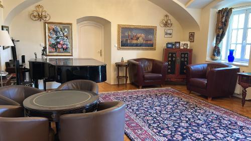 a living room with a piano and leather chairs at Csillaghy Kastély in Bókaháza