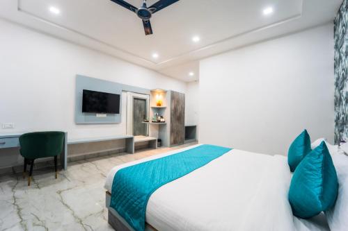 a bedroom with a bed and a desk and a television at Hotel Aura in Bikaner
