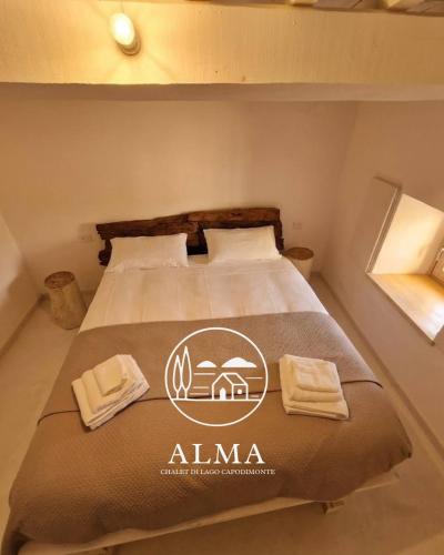 a bedroom with a bed with a alma sign on it at Alma Capodimonte Lake chalet in Capodimonte