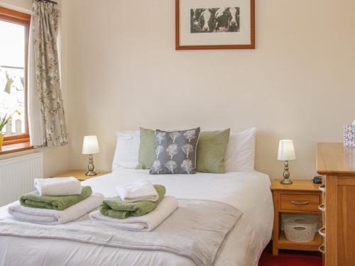a bedroom with a white bed with towels on it at Herdwick Cottage in Much Wenlock