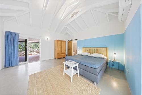 a bedroom with a blue bed and a rug at Koeriboeri Aruba Lodges in Babijn