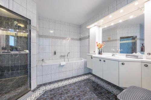 ein Badezimmer mit Badewanne, Waschbecken und Dusche in der Unterkunft Fletcher Hotel - Restaurant Elzenduin in Ter Heijde