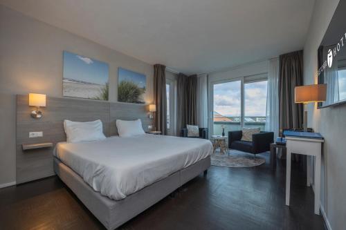 ein Hotelzimmer mit einem großen Bett und einem Schreibtisch in der Unterkunft Fletcher Hotel - Restaurant Elzenduin in Ter Heijde