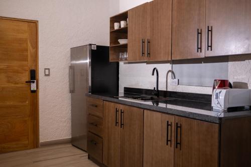 a kitchen with wooden cabinets and a stainless steel refrigerator at Tribe Boutique Resort by Mega Stays in Guayacanes