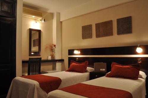 a hotel room with two beds with red pillows at Gregorio I Hotel Boutique in San Salvador de Jujuy