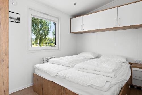 a bedroom with a bed with white sheets and a window at First Camp Lunde - Telemark in Lunde