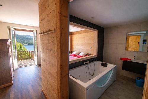 a bathroom with a tub and a bedroom with a bed at Domusigua in Gérardmer
