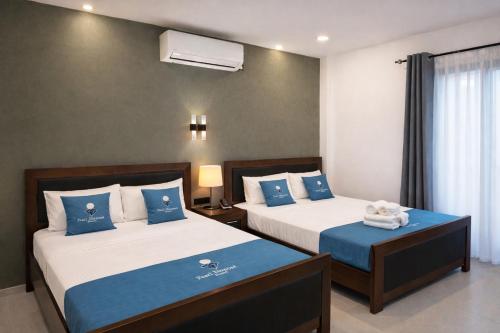 a bedroom with two beds with blue and white pillows at Pearl Diamond Resort in Trincomalee