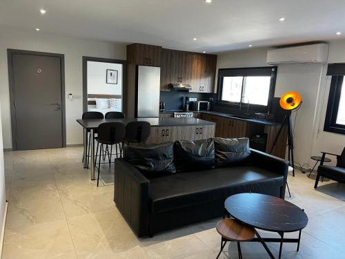 a living room with a black couch and a kitchen at Urban Habitat Suites & Condos in Nicosia