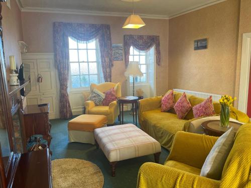 a living room with a yellow couch and chairs at Dufferin Coaching Inn in Killyleagh
