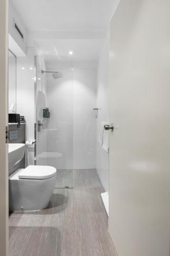 a white bathroom with a toilet and a shower at Ocean Centre Hotel in Geraldton