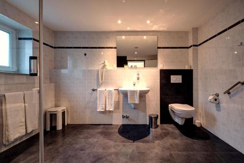 a bathroom with a sink and a toilet and a mirror at Hotel-Restaurant Öhlers in Hannover