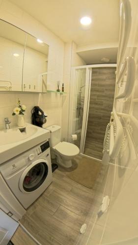 a bathroom with a washing machine and a toilet at Harmony Shore Apartments in Palanga