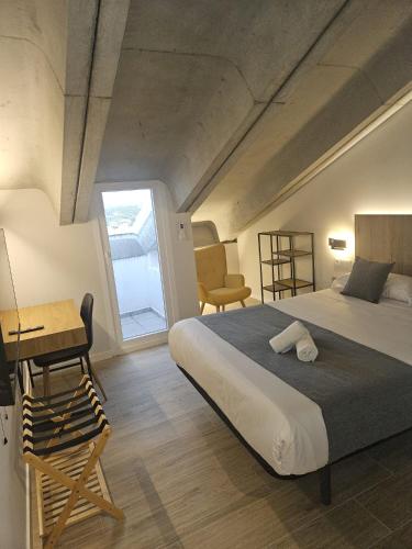 a bedroom with a bed and a desk and a window at Hotel Puerta de la Serrania in Lliria