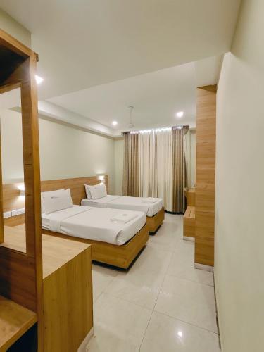 a hotel room with two beds and a mirror at Mareena Regency in Cochin