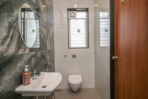 a bathroom with a toilet and a sink and a mirror at 6BHK White Castle Villa in Malavli