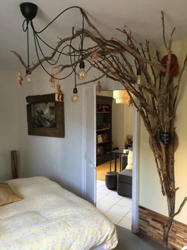 a bedroom with a tree branch chandelier and a bed at Maison Parnasse in Castelnau-de-Guers