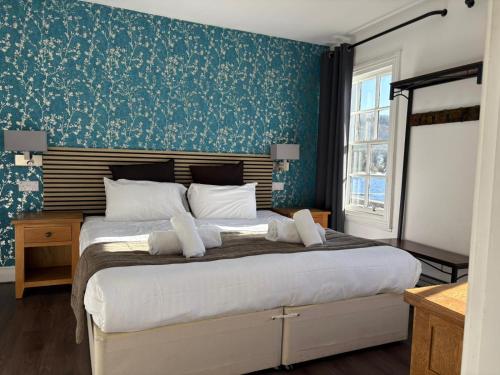 a bedroom with a large bed with blue wallpaper at The Ferry Boat Inn in Ullapool