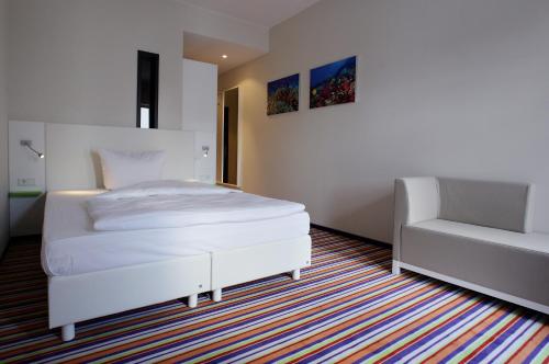 a bedroom with a white bed and a chair at Friendly Cityhotel Oktopus in Siegburg