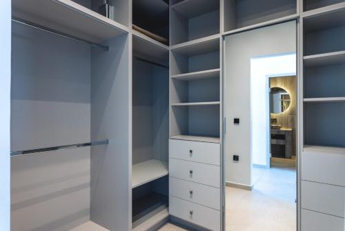 a walk in closet with white cabinets and a mirror at Orama Estate in Koskinou