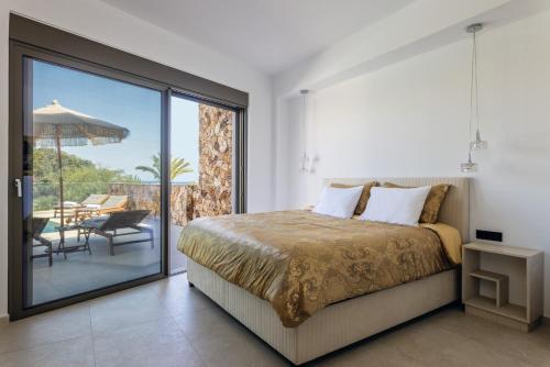 a bedroom with a bed and a balcony with a table at Orama Estate in Koskinou